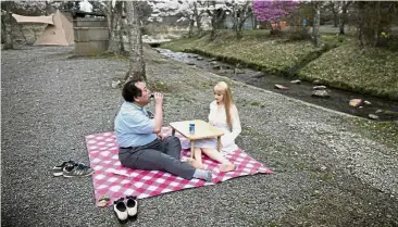  ?? — AFP ?? Faux girlfriend: Nakajima having a picnic with his sex doll Saori under cherry blossoms in Yamanashi prefecture.