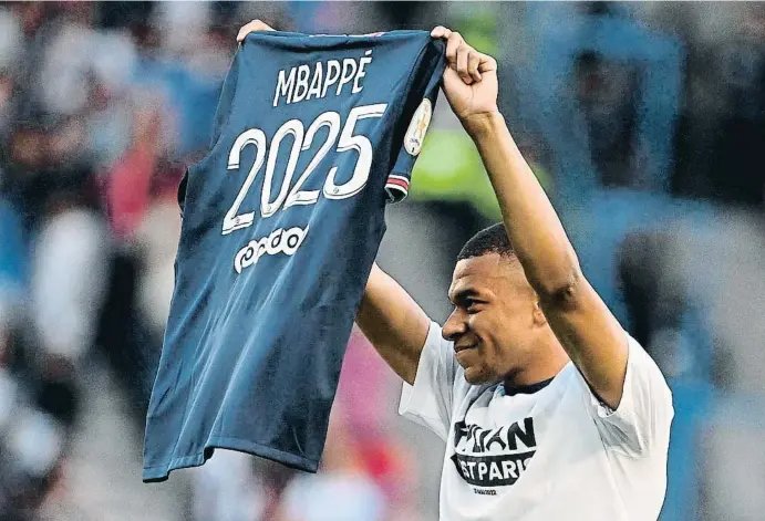  ?? ANNE-CHRI TINE POUJOULAT / AFP ?? El delantero del PSG Kylian Mbappé muestra la camiseta de su renovación, ayer en el Parque de los Príncipes de París