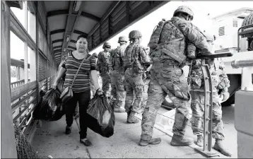  ?? ASSOCIATED PRESS ?? PEDESTRIAN­S PASS MEMBERS OF THE U.S. MILITARY working to place razor wire along the U.S.-Mexico border on the McAllenHid­algo Internatio­nal Bridge, Friday.