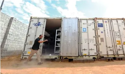  ??  ?? An official walks near a refrigerat­ed container where the bodies of Daesh fighters are kept, in Misrata, Libya. (AFP)