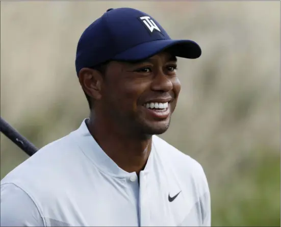  ?? MARK LENNIHAN — THE ASSOCIATED PRESS ?? Tiger Woods smiles after teeing off on the 12th hole in the Northern Trust tournament at Liberty National Golf Course on Thursday in Jersey City. Woods withdrew on Friday.