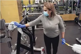  ??  ?? Irma Munoz sanitizes the equipment at Anytime Fitness Westside.