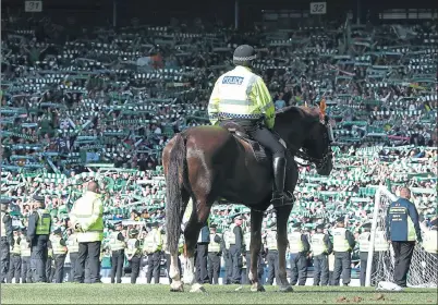  ??  ?? HAMPDEN PARK: A mounted policeman looks on as officers form a cordon in front of Hibernian fans as they celebrate winning the Scottish Cup.