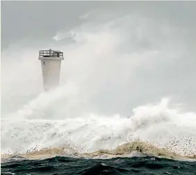  ?? AP ?? Surging waves hit a breakwater and lighthouse in Kiho yesterday.