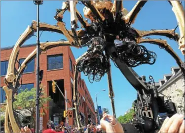  ?? JANET PODOLAK — THE NEWS-HERALD ?? Kumo, the giant spider, is guided through the streets of Ottawa by manipulato­rs perched within it to avoid contact with traffic lights, street signs and people.