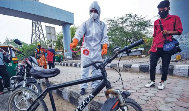  ?? Agence France-presse ?? ↑
A health official sprays disinfecta­nt on a bicycle parked on a road in New Delhi on Thursday.