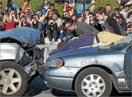  ?? PETE BANNAN — DIGITAL FIRST MEDIA ?? Downingtow­n East High School students Nicky Cacchione and Brendan Dougherty try to revive Burke McFillin (simulated fatal victim) at a mock crash at the school in Uwchlan Monday.