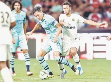  ??  ?? Arsenal’s Mesut Ozil in action with Paris Saint-Germain’s Azzeddine Toufiqui. — Reuters photo