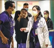  ?? ?? DOCTORS huddle in the COVID-19 unit, which has seen a surge of children who contracted Omicron.