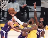  ?? Harry How / Getty Images ?? The Lakers’ LeBron James scores past Deandre Ayton of the Suns on Tuesday.