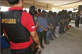  ?? TATAN SYUFLANA / ASSOCIATED PRESS ?? Police officers escort men arrested in a raid on a gay sauna at North Jakarta police headquarte­rs in Jakarta,Indonesia, Monday. Indonesian police detained dozens of men in a weekend raid on a gay sauna in the capital.