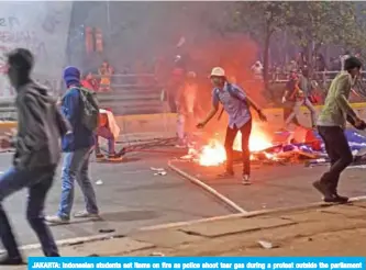  ??  ?? JAKARTA: Indonesian students set items on fire as police shoot tear gas during a protest outside the parliament building in Jakarta yesterday. — AFP