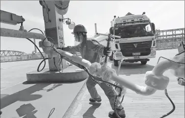  ?? XU CONGJUN / FOR CHINA DAILY ?? An employee shifts the LNG pipeline after filling the transport vehicle at the CNPC LNG center in Jiangsu province.