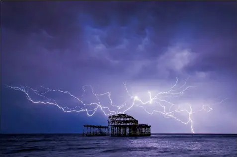  ??  ?? Lightning appears to strike the ruins of Brighton’s West Pier during last night’s electrical storm off the south coast. Others places were affected by lightning strikes and severe floods