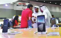  ?? Virendra Saklani/Gulf News ?? Visitors looking at new mobile phones on display at a stall at Gitex Shopper.