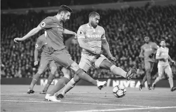  ??  ?? Liverpool’s English midfielder Adam Lallana (left) scores a goal from a tight angle past the attempted block of Stoke City’s English defender Glen Johnson (right) to equalise the score at 1-1 during the English Premier League football match between...
