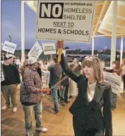  ?? Don Leach Daily Pilot ?? PEOPLE picket outside Newport’s council chambers Tuesday over a proposed homeless shelter in the city.