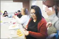  ?? (NWA Democrat-Gazette/Charlie Kaijo) ?? Virginia Figoeroa makes a paper flower Thursday during a meeting of the English Conversati­on Group.