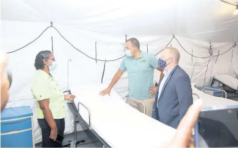  ?? PHOTOS BY NATHANIEL STEWART ?? Eugena Clarke-James, acting CEO of May Pen Hospital, speaks with health minister Dr Christophe­r Tufton (centre) and John McIntyre, chargé d’Affaires at the US Embassy in Kingston, following Wednesday’s official opening of the 40-bed field hospital.