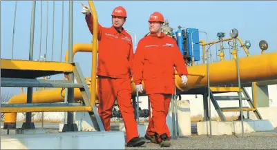  ?? HU QINGMING / FOR CHINA DAILY ?? Two employees of Sinopec walk past a gas pipeline of the company in Puyang, Henan province.