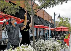  ??  ?? Employees install lights on The Curragh Irish Pub’s patio at the Glen Town Center in north suburban Glenview as the village begins to reopen Saturday.