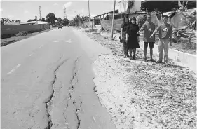  ??  ?? Yong (second left) and Democratic Action Party members stand on a damaged section of the road.