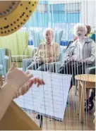  ??  ?? ● Harpist Elfair Grug, right, performed at Pendine Park’s Bryn Seiont Newydd, Caernarfon. Left, residents Mic Foster and Daphne Egan.