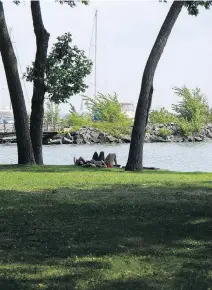  ??  ?? Stretched out under a couple of trees in Centennial Park overlookin­g Lac St-Louis in Beaconsfie­ld, a couple of friends make the most of a bit of shade on a warm summer day.