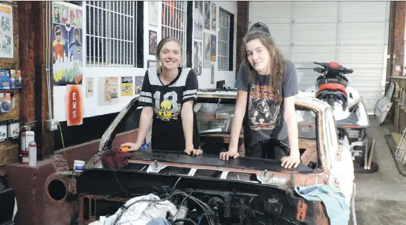  ?? ALYN EDWARDS ?? Sarah Wilkinson and Jasmine Sweet celebrate the disassembl­y of the 1961 Pontiac the pair of Grade 9 friends are working to restore to its original beauty.