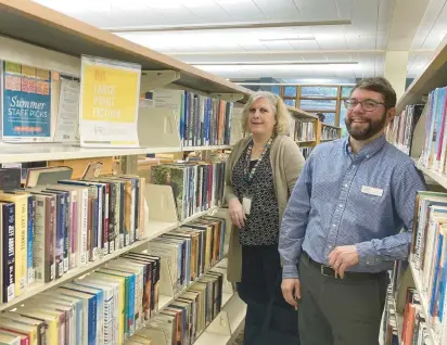  ?? MELINDA MOORE/DAILY SOUTHTOWN ?? Public services librarian Beth Stevens and Matthew Matkowski, head of public services, show some of the Palos Heights Public Library’s collection of largeprint books. Stevens delivers items for the library’s home delivery service, which was formerly Matkowski’s job.