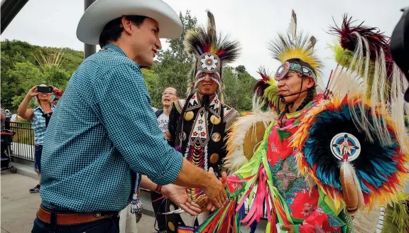  ??  ?? Il premier Justin Trudeau tra danzatori indigeni durante il festival «Calgary Stampede». Il primo ministro canadese ha promesso una svolta nella gestione delle comunità indigene (Ap)