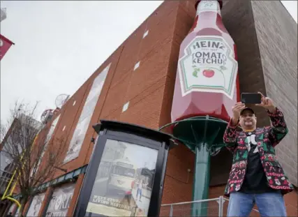  ?? Tim Robbibaro/For the Post-Gazette ?? Brad E. Burmeister, exhibits production director at the Heinz History Center, snaps a selfie Saturday with the newly installed Heinz ketchup bottle. The bottle previously was displayed at the former Heinz Field.