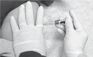  ?? TED S. WARREN/AP ?? A medical assistant at Sea Mar Community Health Center in Seattle gives a patient a flu shot. Experts say it’s not too late to get one.