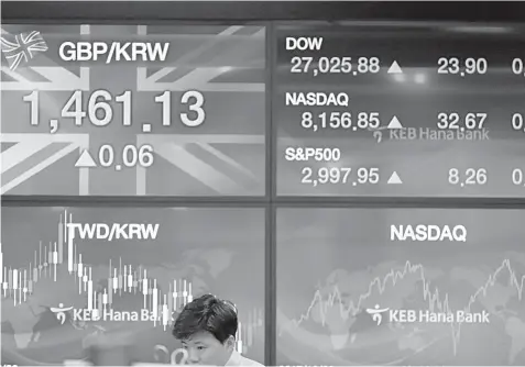  ??  ?? A currency trader monitors stocks at the foreign exchange dealing room in Seoul, South Korea, Friday, Oct. 18, 2019. Share prices retreated in Asia after China reported Friday that its economy grew at an annual rate of 6.0% in the latest quarter. ASSOCIATED PRESS