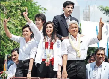  ?? PORNCHAI KITTIWONGS­AKUL/AFP ?? Yingluck Shinawatra (centre), sister of ex-Prime Minister Thaksin Shinawatra, greets supporters after her registrati­on as the Pheu Thai party candidate in Bangkok before elections in 2011.