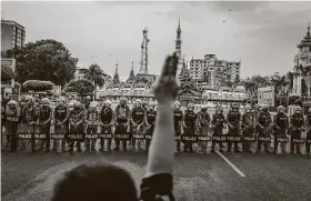  ?? Getty Images ?? A protester makes a three-finger salute in front of a row of riot police, who are holding roses given to them by protesters, on Saturday in Yangon, Myanmar.