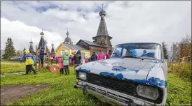  ?? AP 2018 ?? People stand in a field with the 18th century Trinity Church in the background in the village of Nyonoksa, Russia, in 2018. A testing range was set up near the village in 1954, when the Soviet Union’s missile program was still in its nascent phase.