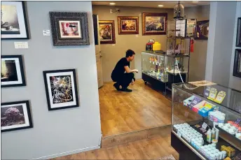  ?? COURTESY PHOTO ?? The Vault co-owner Noah Trodick inspects locally-made glass at his dispensary. The store also features a large gallery of New Mexico artists.