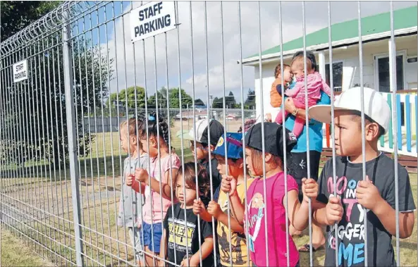  ??  ?? OPPOSED: Staff and children of Te Ara Metua Punanga Reo Kuki Airani look out at the proposed business site which will house a service station, retail shops and a liquor store.