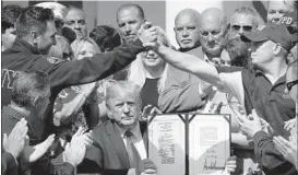  ?? WIN MCNAMEE/GETTY ?? First responders and their families celebrate as President Trump signs the bill.