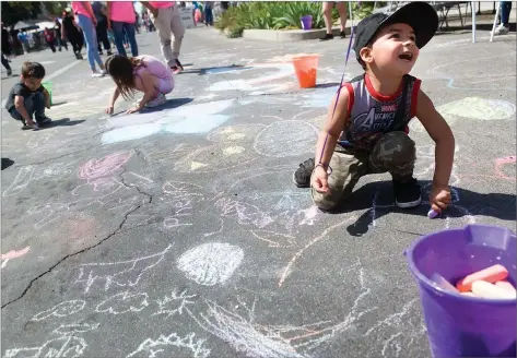  ?? RECORDER PHOTOS BY CHIEKO HARA ?? Chalk artist Phelix Mckneely, 3, enjoys drawing on the huge canvas Saturday, April 28, at the annual Iris Festival downtown Portervill­e.