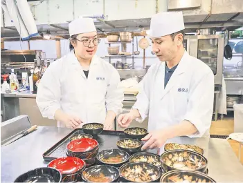  ?? — The Japan News ?? Vincent Pham, left, learns the spirit of hospitalit­y and how to arrange bowls from his senior at Akasaka Asada in Minato Ward, Tokyo.