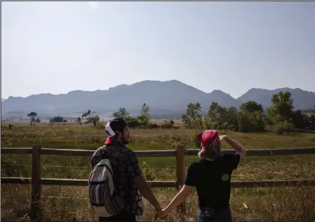  ?? Timothy Hurst / Staff Photograph­er ?? Martin Guerrero, left, and Rachelle Parker, both visiting from Austin, Texas, look toward the foothills that are partially obscured by smoke from wildfires in the West. They were heading out for a hike Thursday on the South Boulder Creek West Trail.