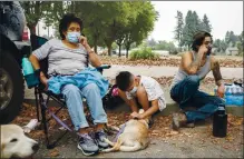  ?? KARL MONDON — STAFF PHOTOGRAPH­ER ?? Gabriela Carr, 61, Julian Rizo, 9, Jordan Castaneda, 30, with their dogs Little Boy and Spanky, wait at an evacuation site after fleeing their homes in the Glass Fire in Santa Rosa on Monday.