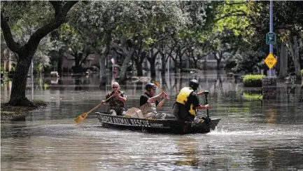  ?? Karen Warren photos / Houston Chronicle ?? Precinct 1 constable officer Chris Kendrick, along with Houston SPCA’s Octavio Gonzalez and Bon Wilson, go out in a boat at Memorial and Crossroads to rescue a cat on Tuesday.