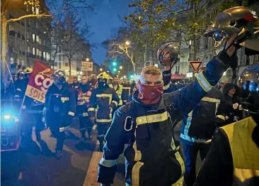  ?? GETTY IMAGES ?? French firemen and members of the CGT union march through the streets of Paris chanting against President Emmanuel Macron as thousands take to the streets in support of the National Strike on a crucial day between the government and the unions over pension reforms in Paris.