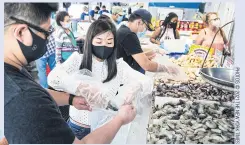  ??  ?? Wendy Liu and Yang Zhao fill their bags with shrimp.