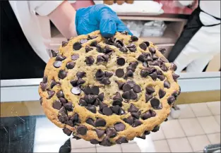  ??  ?? The chocolate chip cookie at Vande Walle’s Candies measures nearly 7 inches across, and it’s jam-packed with chocolate chips.