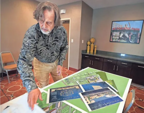  ??  ?? Developer Kenny Farrell pulls out ambitious plans for a new mixed-use developmen­t being built off Interstate 55 in Marion, Arkansas. Called Angelo’s Grove, the developmen­t was stalled during the recession but is now starting to take off. JIM WEBER/THE...