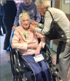  ?? PEG DEGRASSA - DIGITAL FIRST MEDIA ?? Birthday party guest of honor Marie Wissing, 100, is all smiles as friends Vera Miller, back, and Dolores Young, right, pin on a birthday button and corsage and place a crown on her head, as she enters the room where her celebratio­n is about to take place.